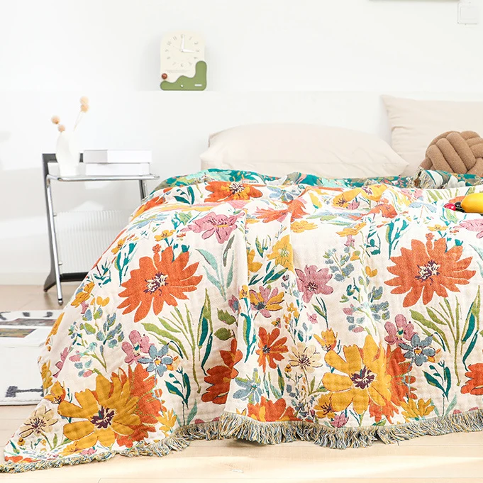 Wendbare Sofadecke aus Baumwollgaze mit Quasten und leuchtendem Blumenmuster