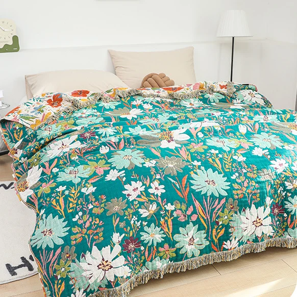 Wendbare Sofadecke aus Baumwollgaze mit Quasten und leuchtendem Blumenmuster